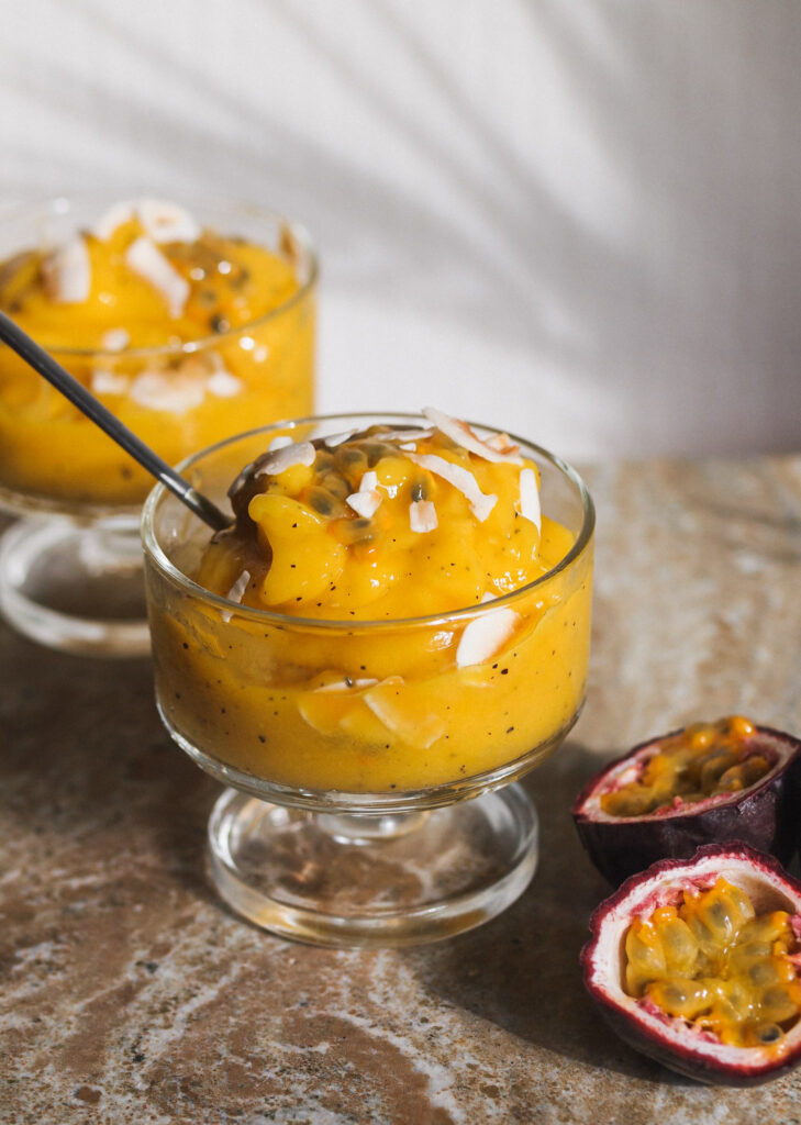 Healthy Tropical Sunshine Sorbet in a glass dish with a sliced passionfruit beside