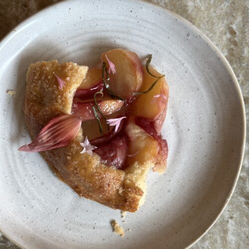 a slice of peach rosemary galette with edible flower decorations