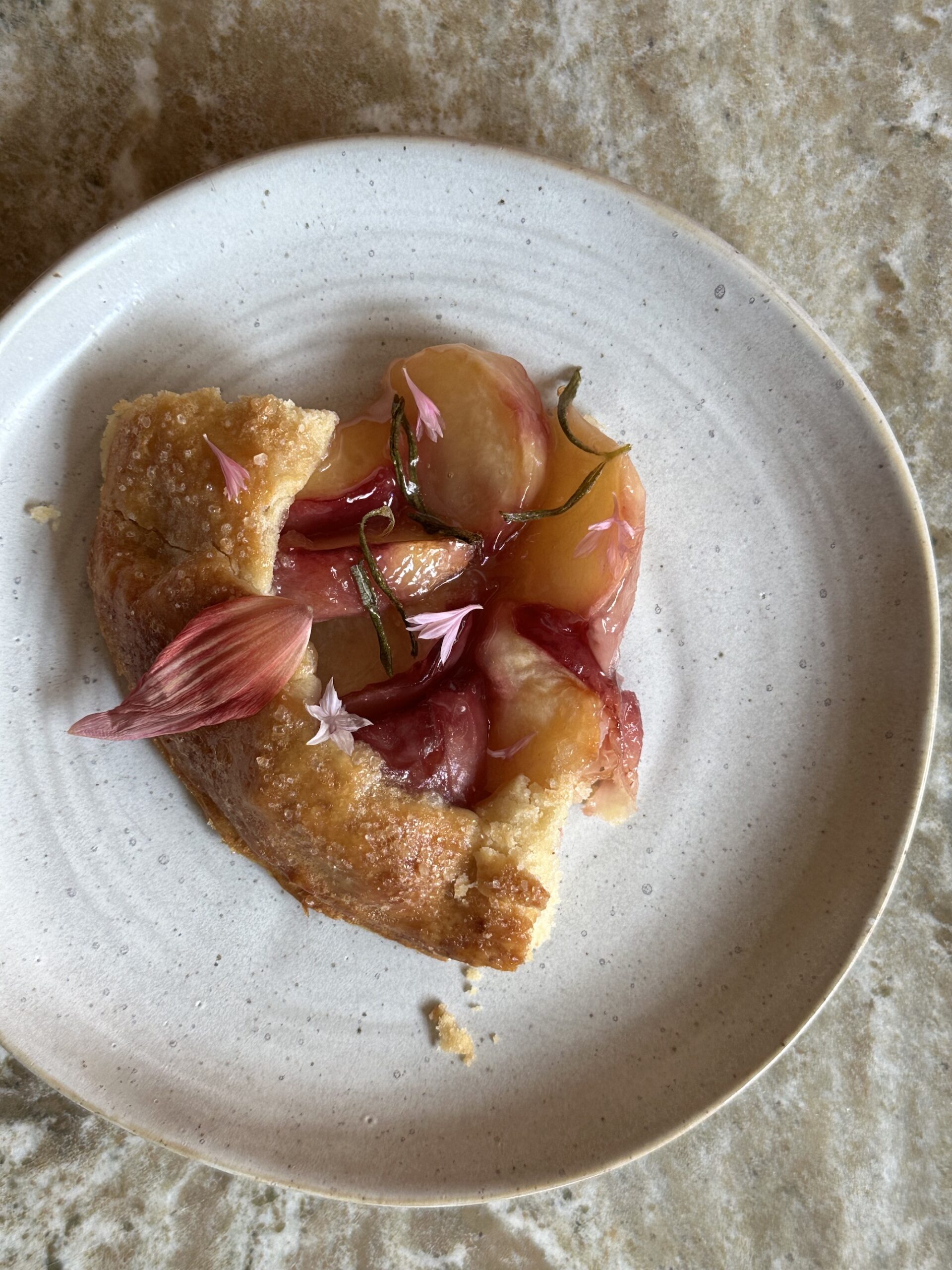 a slice of peach rosemary galette with edible flower decorations